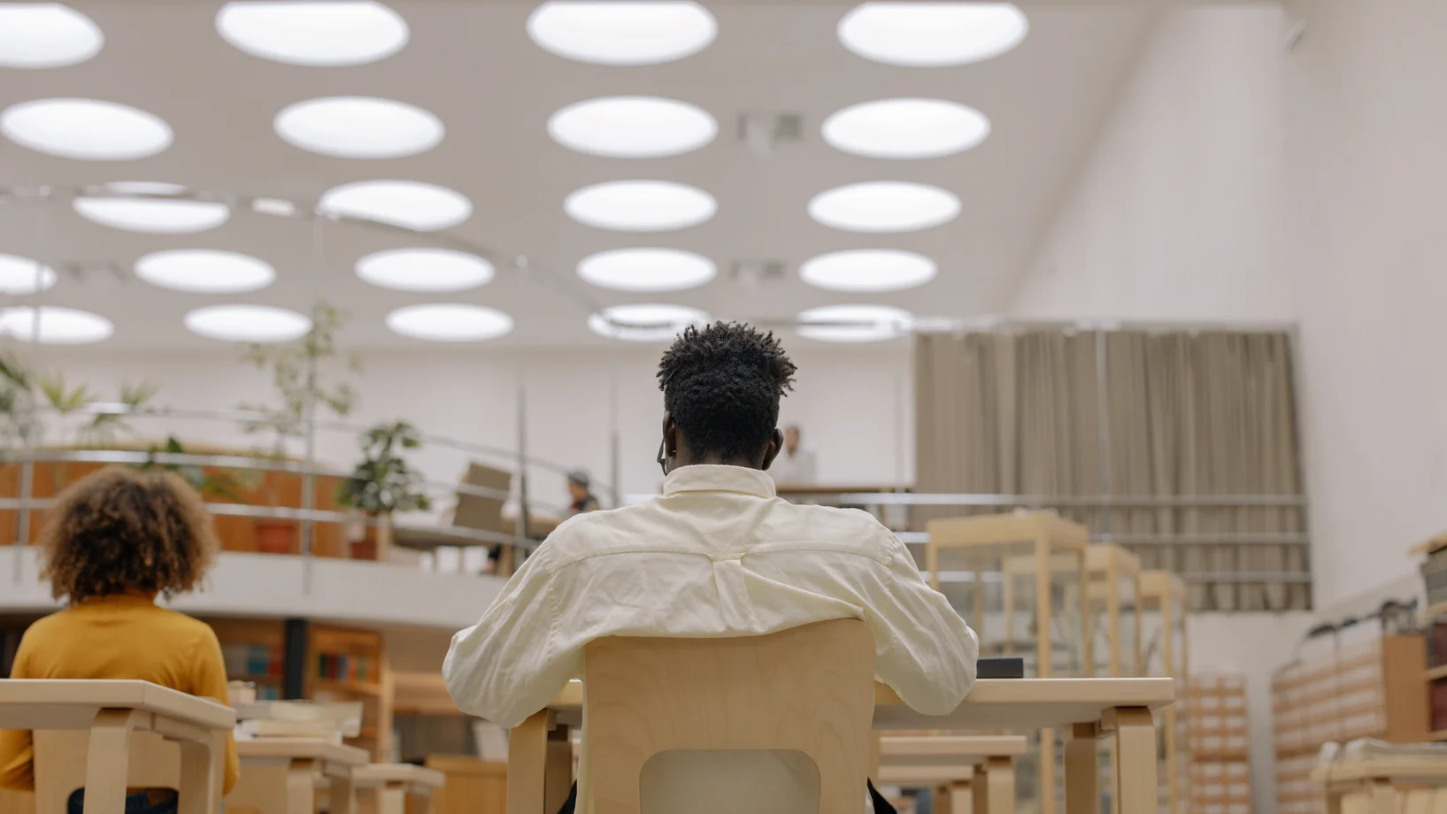 Signore vestito in biancho seduto in un'aula